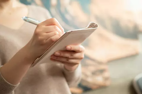 femme-qui-a-un-cahier-et-un-crayon-dans-la-main-autotest-gaspi-problèmes-digestifs