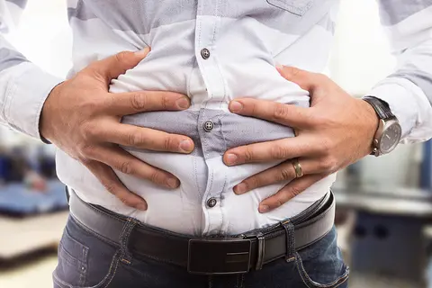 homme-en-chemise-blanche-se-tient-les-mains-sur-le-ventre-sensation-de-plenitude-flatulences-bonne-digestion-gaspan-schwabe-pharma