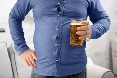 Mann hält ein Bierglas – Symbol für lifestylebedingte Ursachen von Blähbauch und Blähungen.