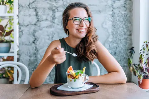 Frau isst Joghurt mit Früchten – Symbol für darmfreundliche Ernährungsgewohnheiten bei Blähungen.