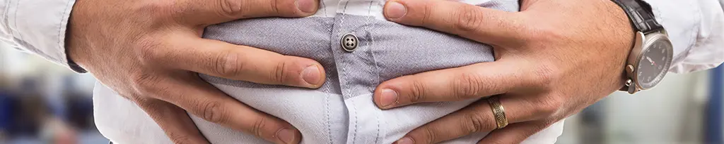 homme-en-chemise-blanche-se-tient-les-mains-sur-le-ventre-sensation-de-plenitude-flatulences-bonne-digestion-gaspan-schwabe-pharma