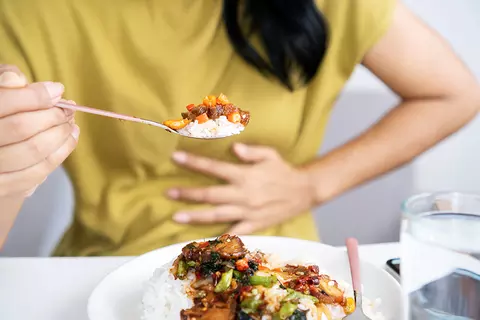 femme-manger-se-tenir-la-main-au-ventre-irritant-bien-digérer