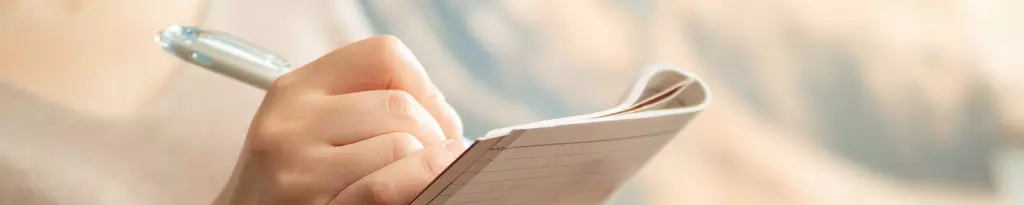 frau-sitzt-und-schreibt-in-ein-notizbuch-gaspan-selbsttest-verdauungsprobleme